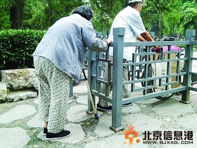 网友拍摄的两位老人艰难通过公园小门。