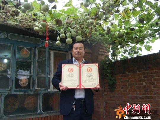 唐山曹妃甸农民郑宝平手捧世界纪录证书，乐呵呵地与他的421个葫芦娃合影留念。 孙溢 摄