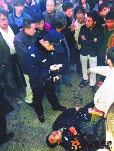 打人保安被众人围殴倒在地上。