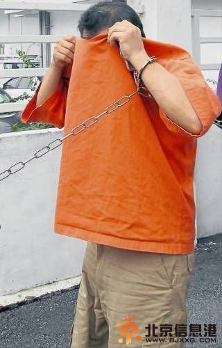 嫌犯被带往法庭延扣时，以上衣遮脸掩盖面目。（马来西亚《南洋商报》）