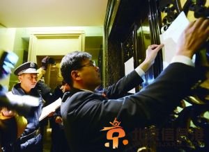 1月9日，朝阳法院执行局的法官将公告贴在门上，同时对房间内的人员出示了证件。