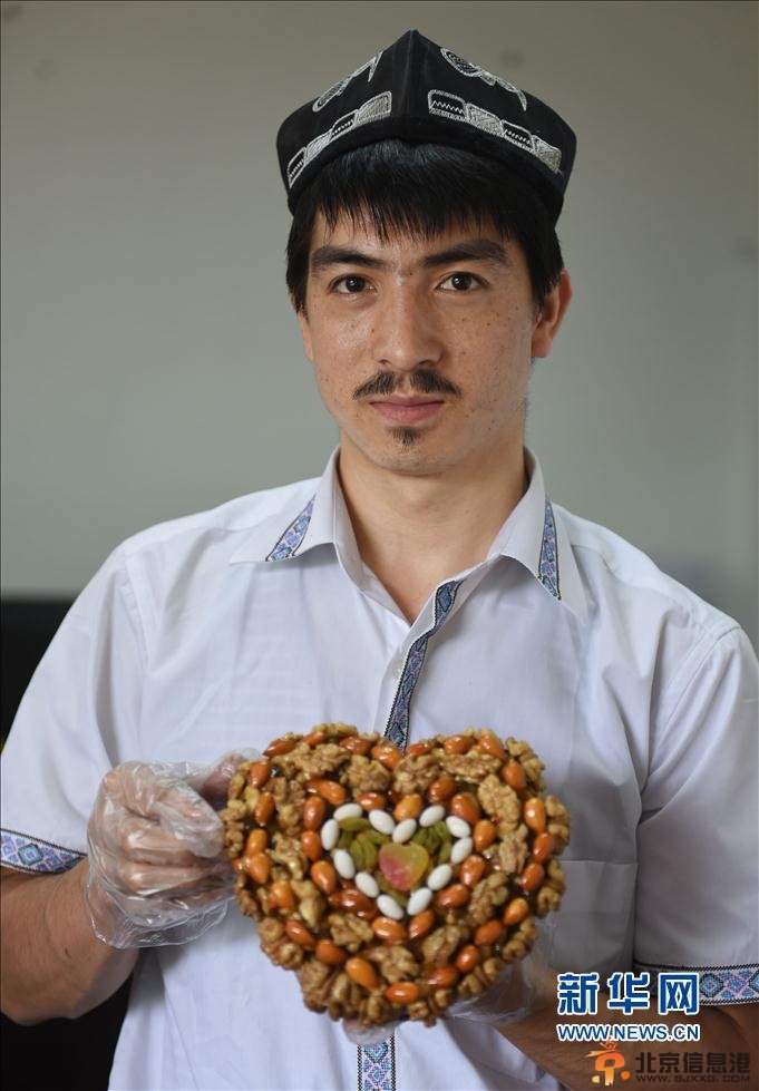 5月22日，阿迪力和蒋春杨一起将核桃仁倒入盛有糖稀的锅中。 新华社记者 李尕 摄