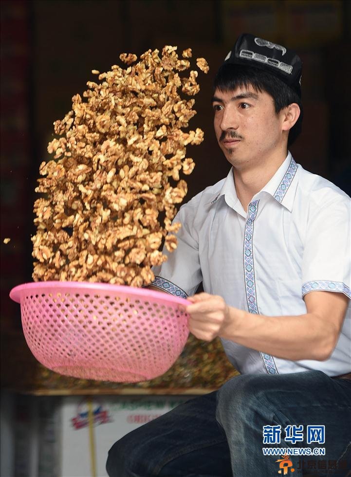 5月22日，阿迪力和蒋春杨一起将核桃仁倒入盛有糖稀的锅中。 新华社记者 李尕 摄
