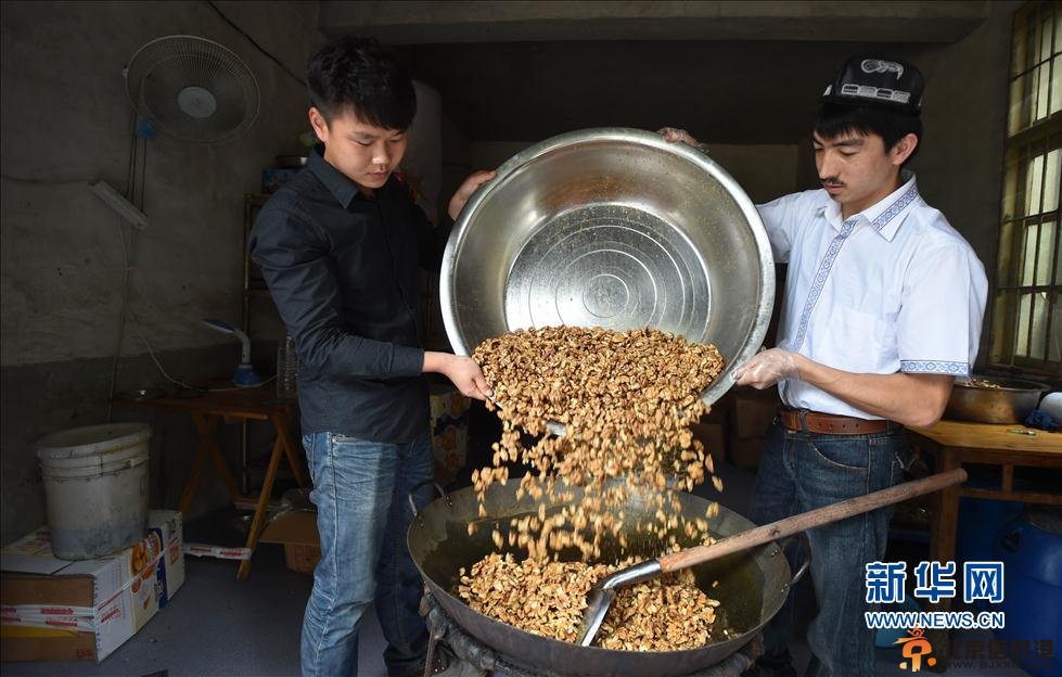 5月22日，阿迪力和蒋春杨一起将核桃仁倒入盛有糖稀的锅中。 新华社记者 李尕 摄